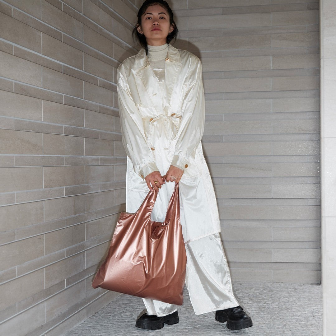 whb-superb LOQI Tragetasche in mattem Roségold, getragen von einer Frau in einem hellen, eleganten Outfit.