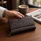 Schwarze Bench Wonder Geldbörse aus Leder mit großem Logo-Prägedruck auf einem Holztisch neben einer Kaffeetasse