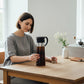 whb-superb Hario Mizudashi Cold Brew Kaffeekanne aus Glas mit schwarzem Filter und Deckel auf einem Holztisch