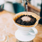 whb-superb HARIO V60 02 Keramik Kaffeefilter in Weiß beim Aufgießen von Kaffee mit einem Papierfilter