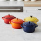 whb-superb Le Creuset Mini-Cocotte Set aus emailliertem Gusseisen in Rot, Orange, Gelb und Blau auf Marmorplatte