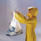 whb-superb LOQI Einkaufstasche Fuji aus recyceltem Taft in einer gelben Regenjacke unter Wasserstrahlen