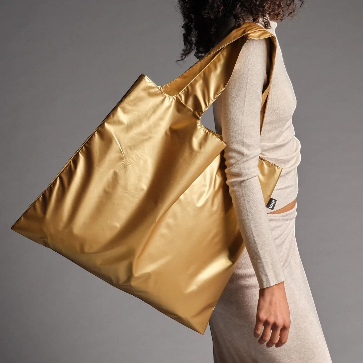 whb-superb LOQI Tragetasche in mattem Gold aus wasserfestem Polyester, getragen über der Schulter